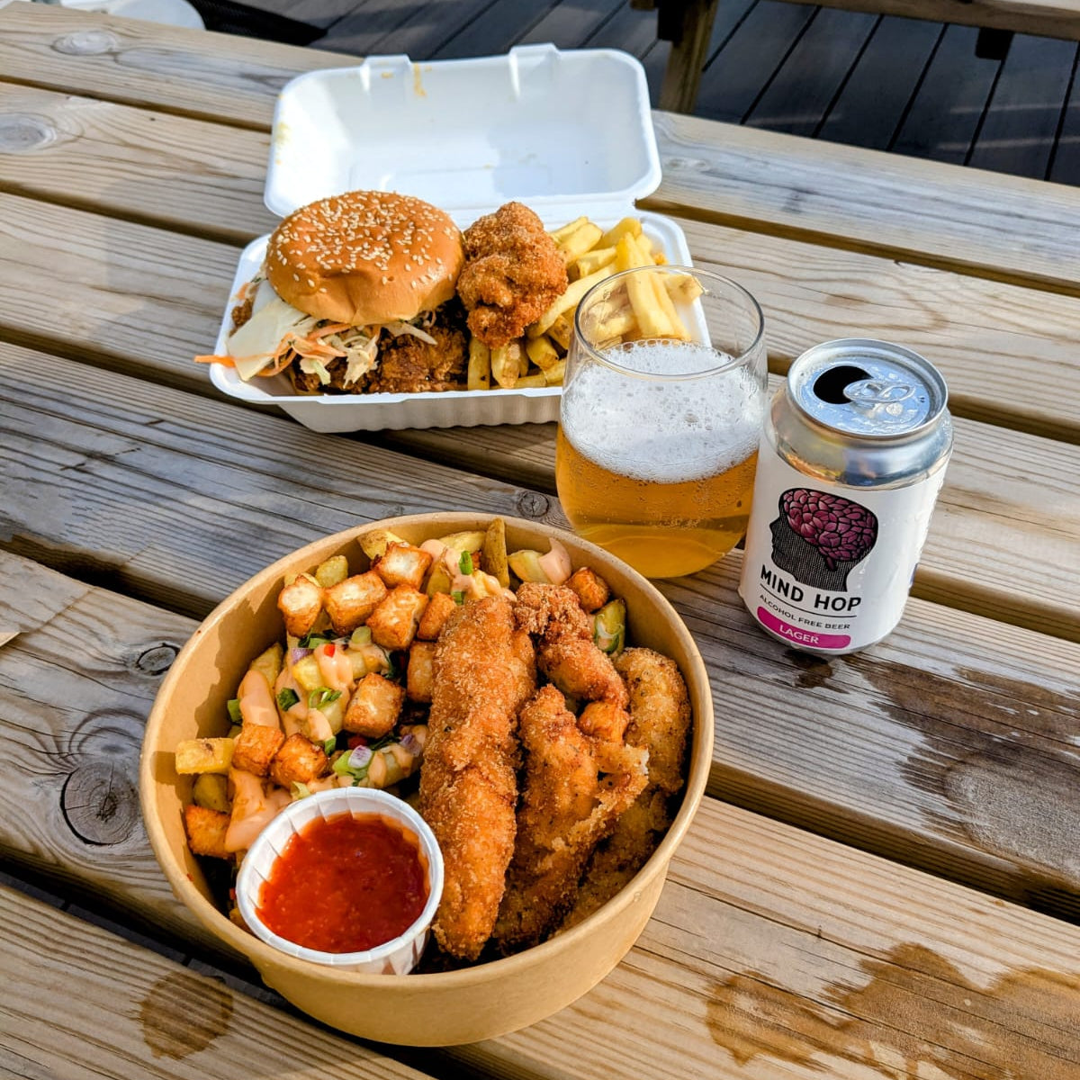 Outdoor setting with food and a Mind Hop Alcohol Free Lager on a wooden table